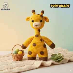 Handmade crochet giraffe plush toy in yellow and brown yarn, displayed on a knitted blanket with a small basket of yarn balls and a succulent deco