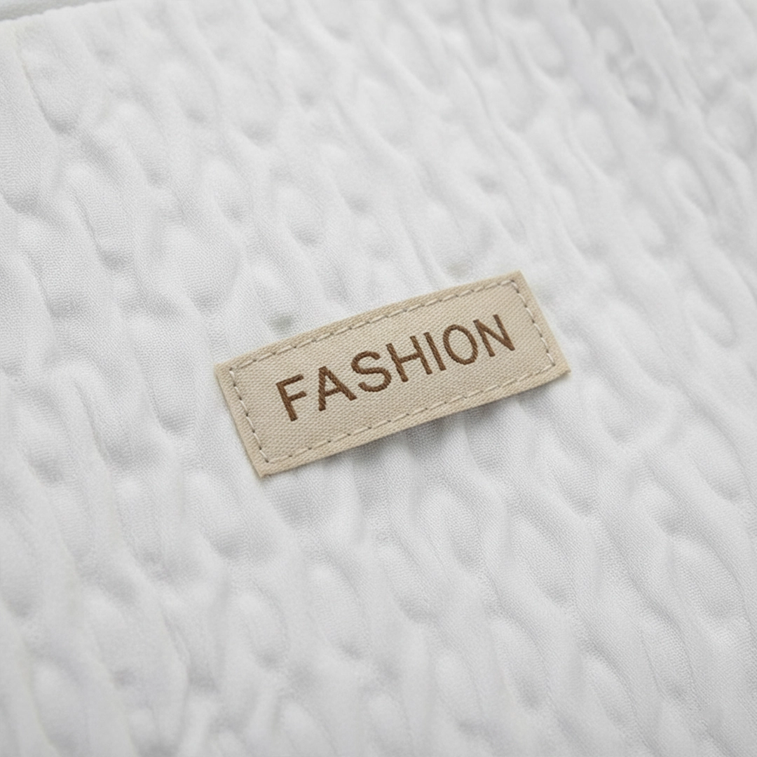 TORTKART White Textured Backpack worn by a woman in a yellow sweater sitting in a sunny urban city street. Fashionable bubble-texture daypack for college or casual travel.