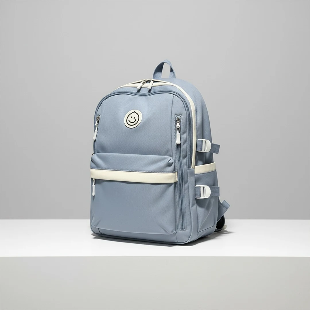 Color-blocked backpack in dusty blue and cream beige, featuring multiple zippered compartments, front buckle straps, and utility side pockets, styled with a rolled map and sunglasses.