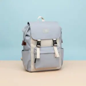 ZSITIZ Flap Top Backpack in color-blocked light gray and beige/cream, featuring front buckles, side pockets, and a rectangular logo patch, on a color background.