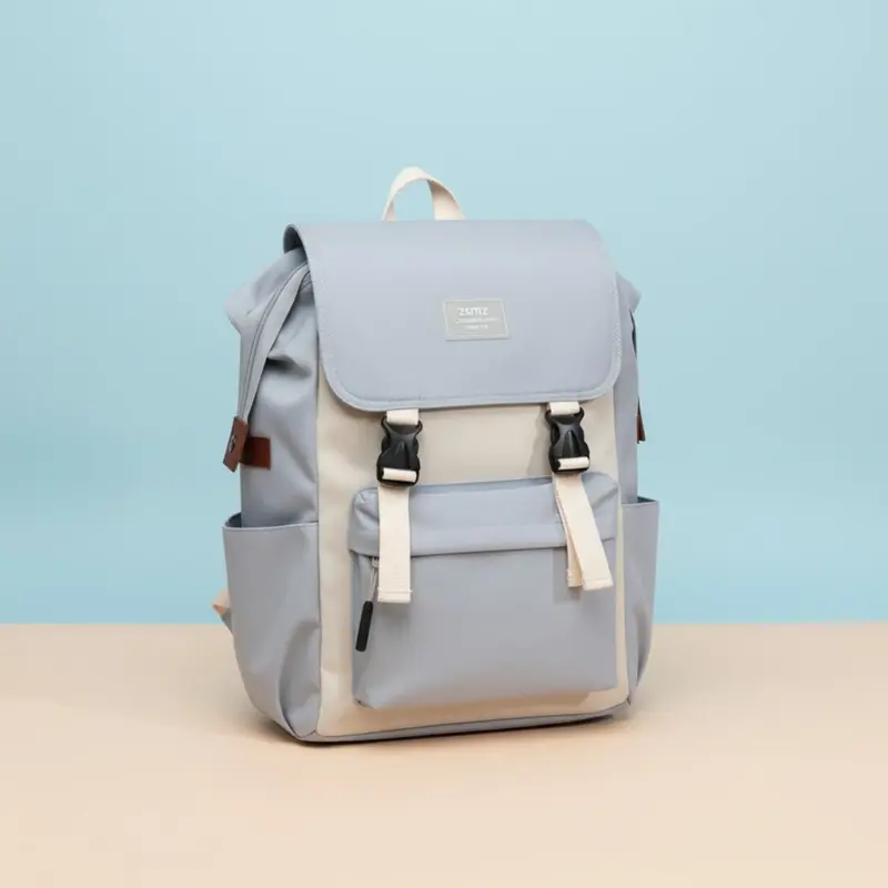 ZSITIZ Flap Top Backpack in color-blocked light gray and beige/cream, featuring front buckles, side pockets, and a rectangular logo patch, on a color background.