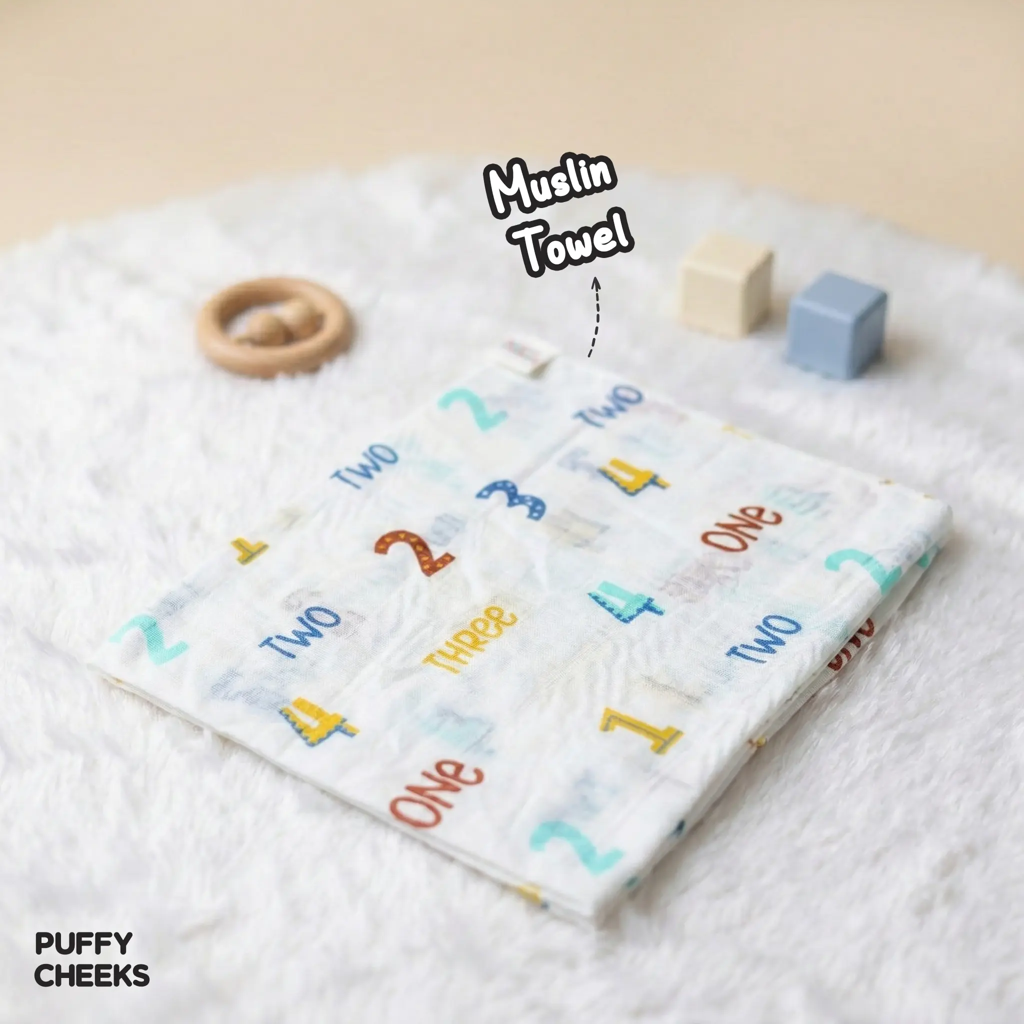 A set of three Puffy Cheeks small square muslin towels in individual clear packaging, featuring a number and word print, a floral sun print, and a colorful abstract shape print.