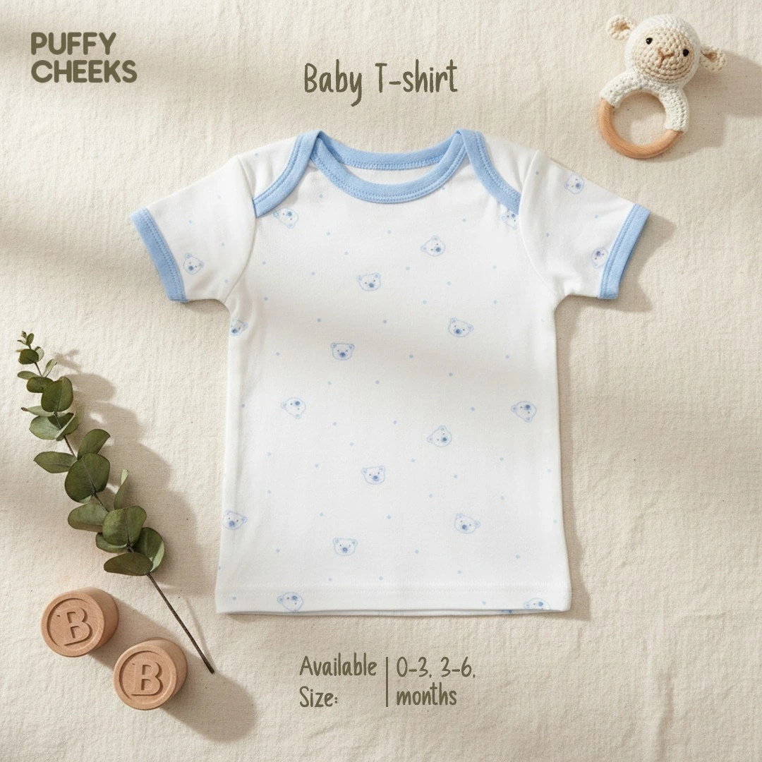 Premium 3-piece baby t-shirt set showcasing a soft white cotton short sleeve infant tee with a light blue envelope neck border and a mini teddy bear pattern, styled flat on a cream fabric backdrop with wooden blocks.