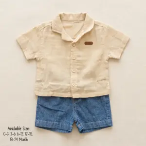 A casual baby boy summer clothing set laid flat on a light beige background, featuring a beige half-sleeve button-down shirt with a notch lapel collar, paired with classic blue denim jean shorts.