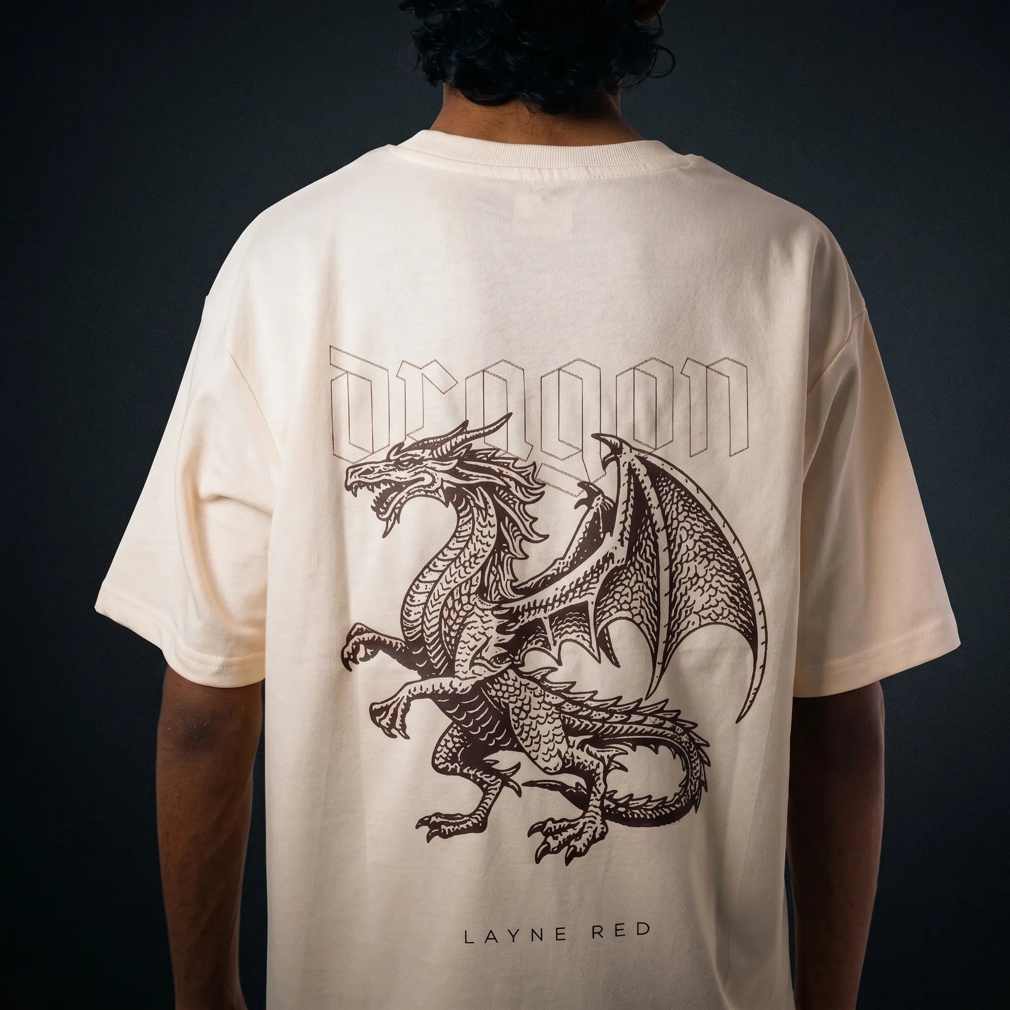 Back view of Layered heavy-set cream oversized t-shirt showcasing a large central dragon graphic with orange flames.