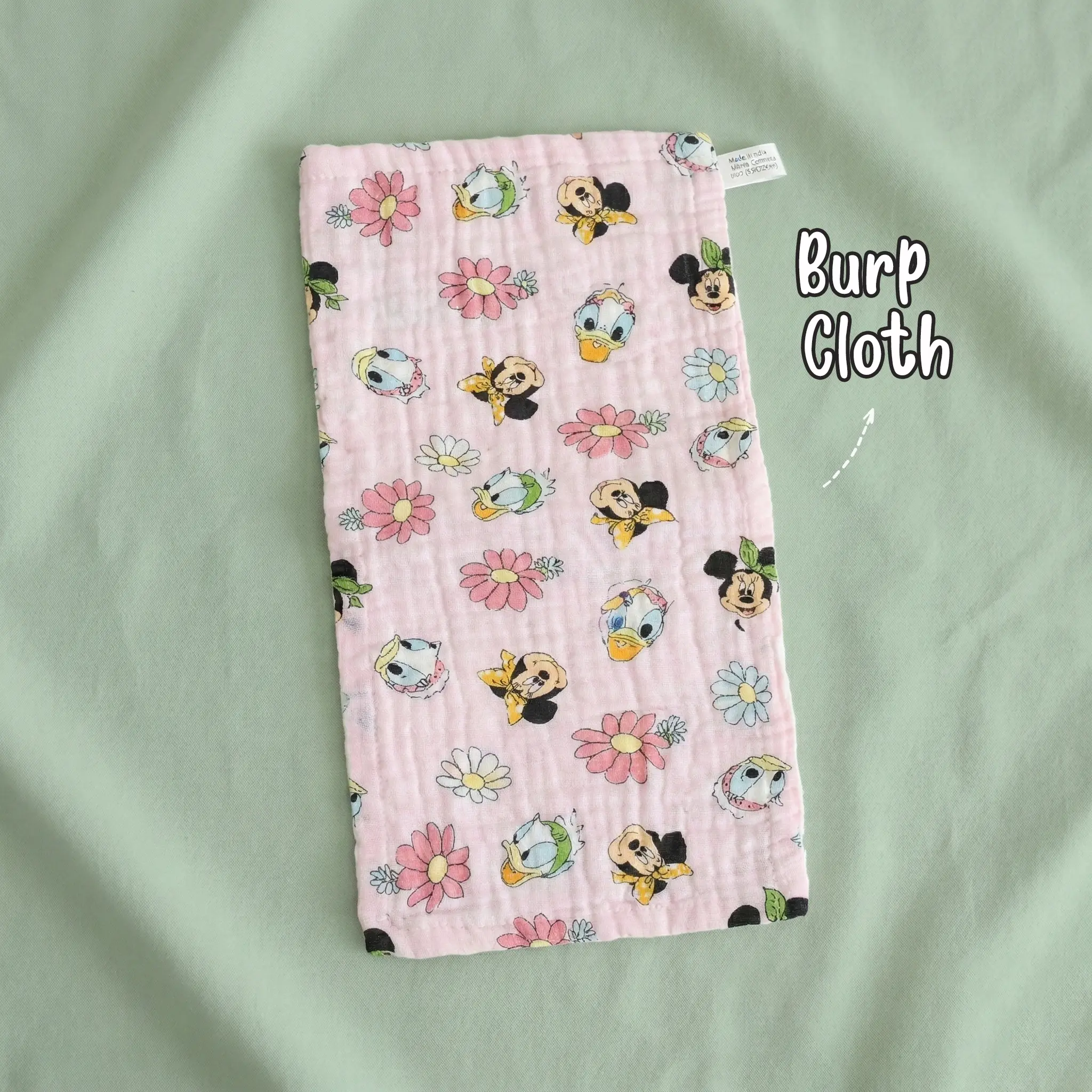 The file 4 (15).jpg shows a single rectangular cream-colored muslin baby burp cloth by Puffy Cheeks with a crinkled texture, patterned with a vibrant fruit print of kiwis, lemons, cherries, green apples, and purple grapes interspersed with tiny blue stars, laid flat on a soft purple fabric surface.