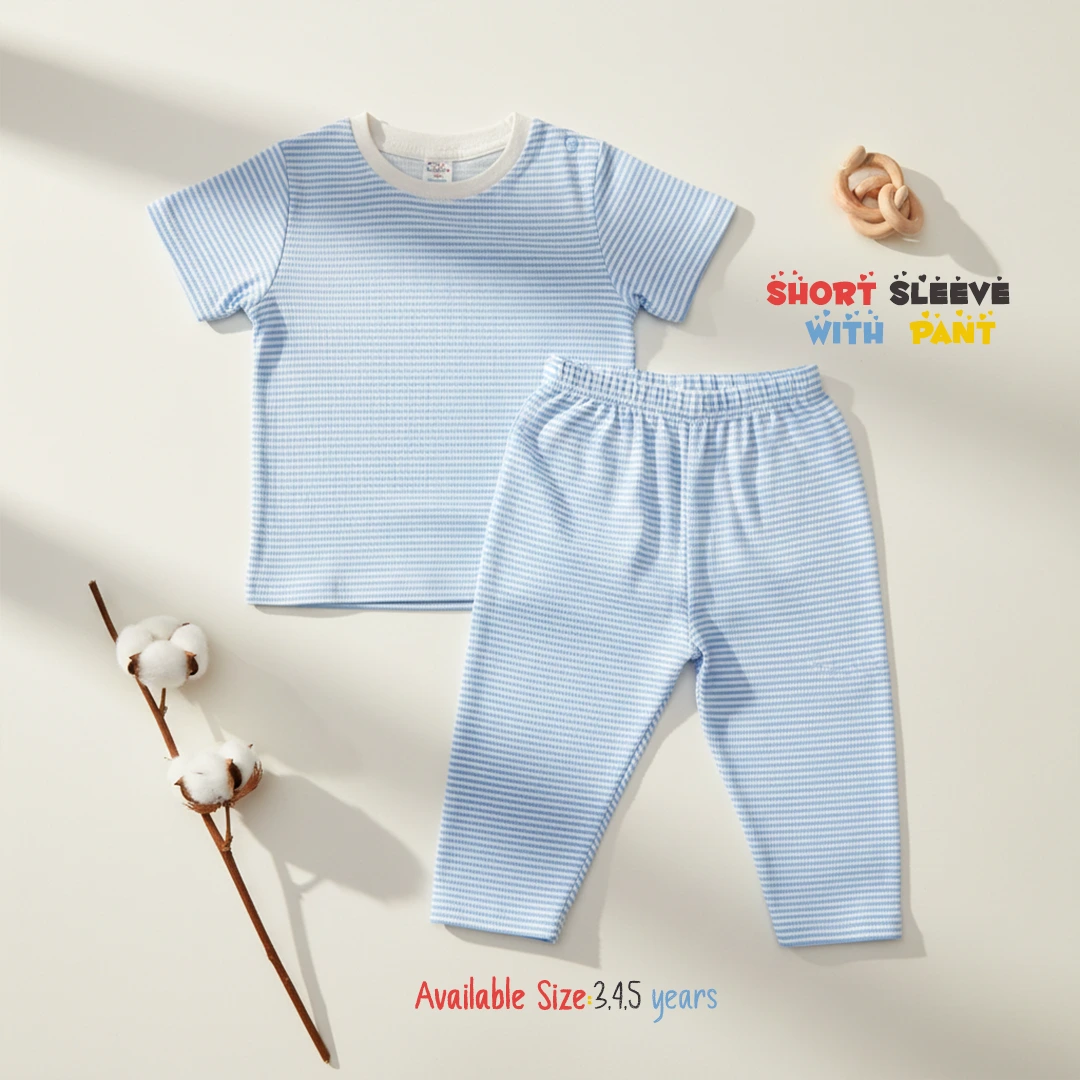 The image displays a light blue and white horizontally striped toddler lounge set, consisting of a short sleeve round neck t-shirt with a solid white collar trim and matching long pants, laid flat on a white surface next to a wooden rattle toy and a cotton branch.