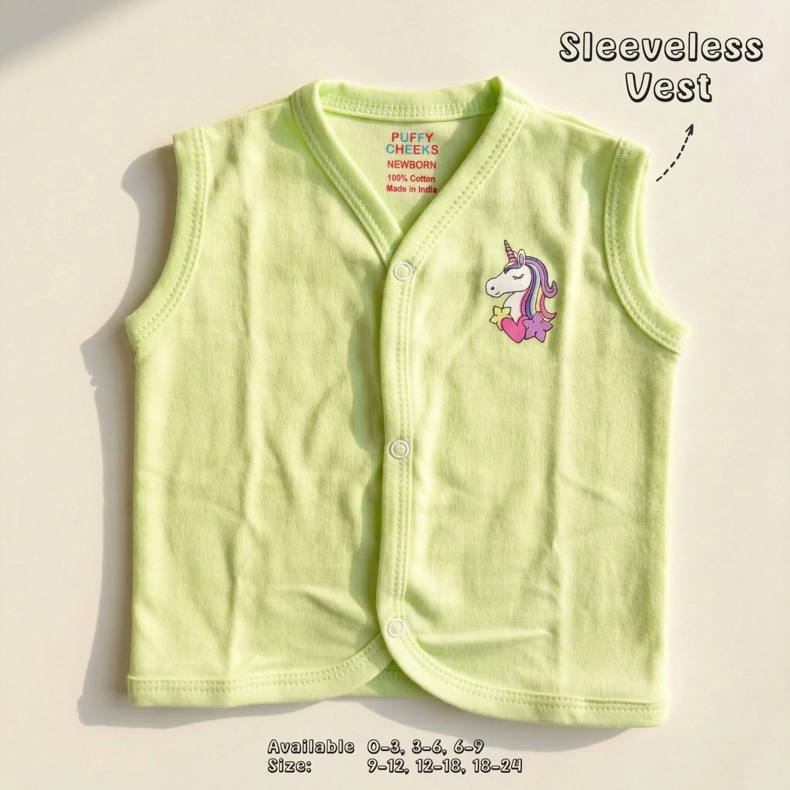 The image shows a light lime green sleeveless baby vest by Puffy Cheeks featuring a v-neckline and three white snap-button front closures. The vest highlights a colorful unicorn motif on the left chest with a purple and pink mane and a small heart accent, laid flat on a smooth white surface.