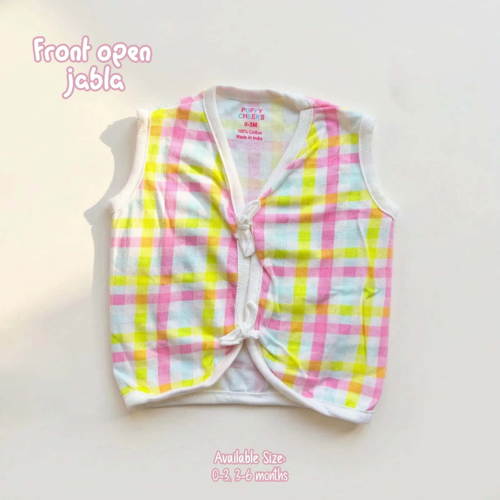 The image shows a lightweight, sleeveless front-open baby jabla by Puffy Cheeks featuring a colorful pastel plaid check pattern in pink, yellow, mint green, and white. The garment is designed with a v-neckline, soft white fabric trim along the borders, and two fabric tie-front closures at the center, flat-laid on a clean white surface.