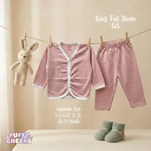 Baby full sleeve front-open top and matching pants set by Puffy Cheeks featuring a faint all-over white dot print on a dusty pink cotton fabric, with the long-sleeve cardigan top showing a white ribbed v-neck trim and snap-button closure hanging from a clothesline with wooden pegs next to matching elastic-waist pants and a small knit bunny toy, displayed above a pair of sage green knit infant booties on a soft surface.